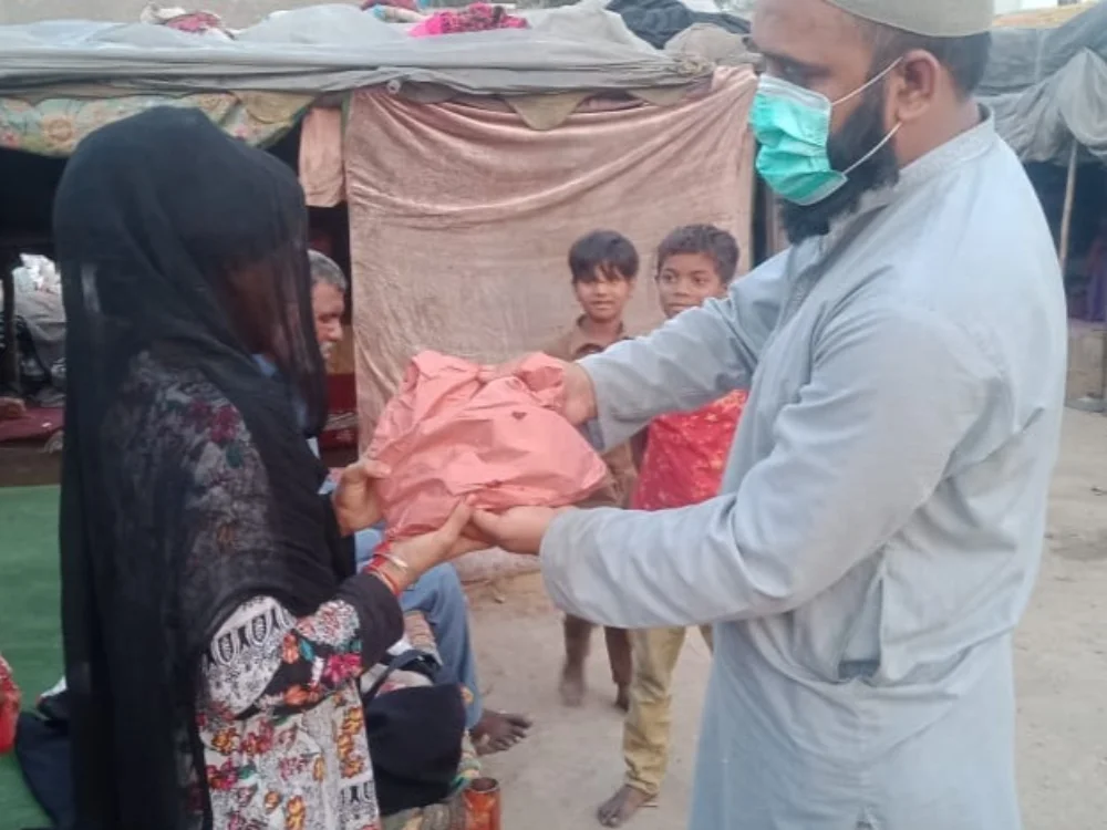 Un bénévole remet une aide alimentaire à une famille dans le cadre d’une action humanitaire soutenue par Nazkot Farm.